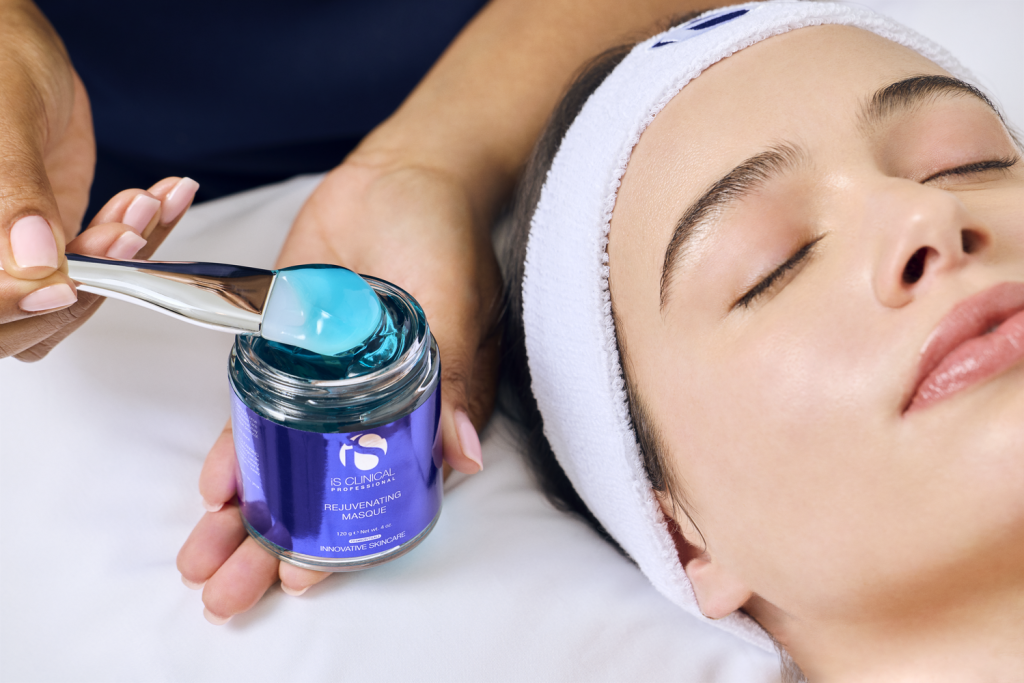 Woman applying rejuvenating masque to face of client during fire & ice facial treatment.