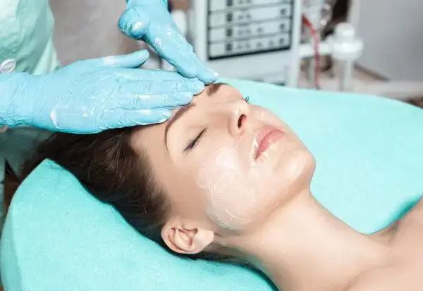 Esthetician providing a brightening Vitamin C facial to a relaxed woman
