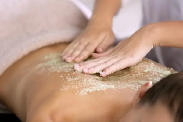 Exfoliating spa treatment delivered on a client's back to smooth skin