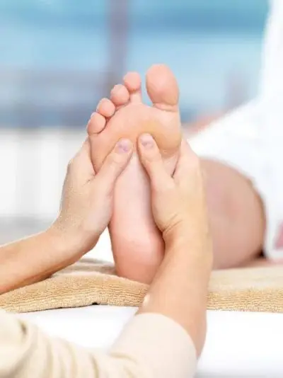 Therapist's hands shown giving a client a foot massage