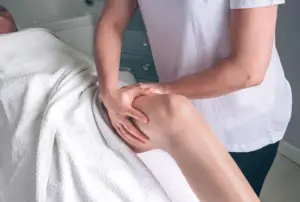 Massage therapist positioning client's lg for lymphatic drainage massage