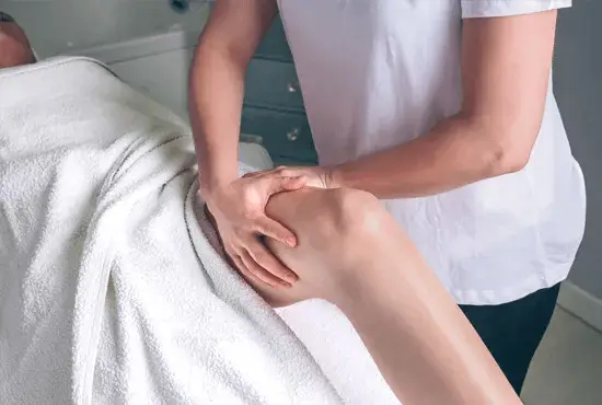 Massage therapist positioning client's lg for lymphatic drainage massage