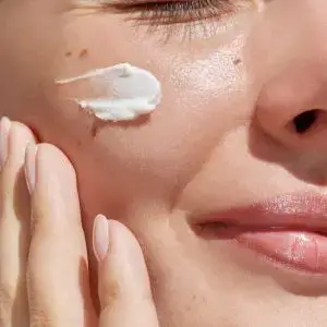 Woman applying Vitamin C serum to her face to maintain glowing skin
